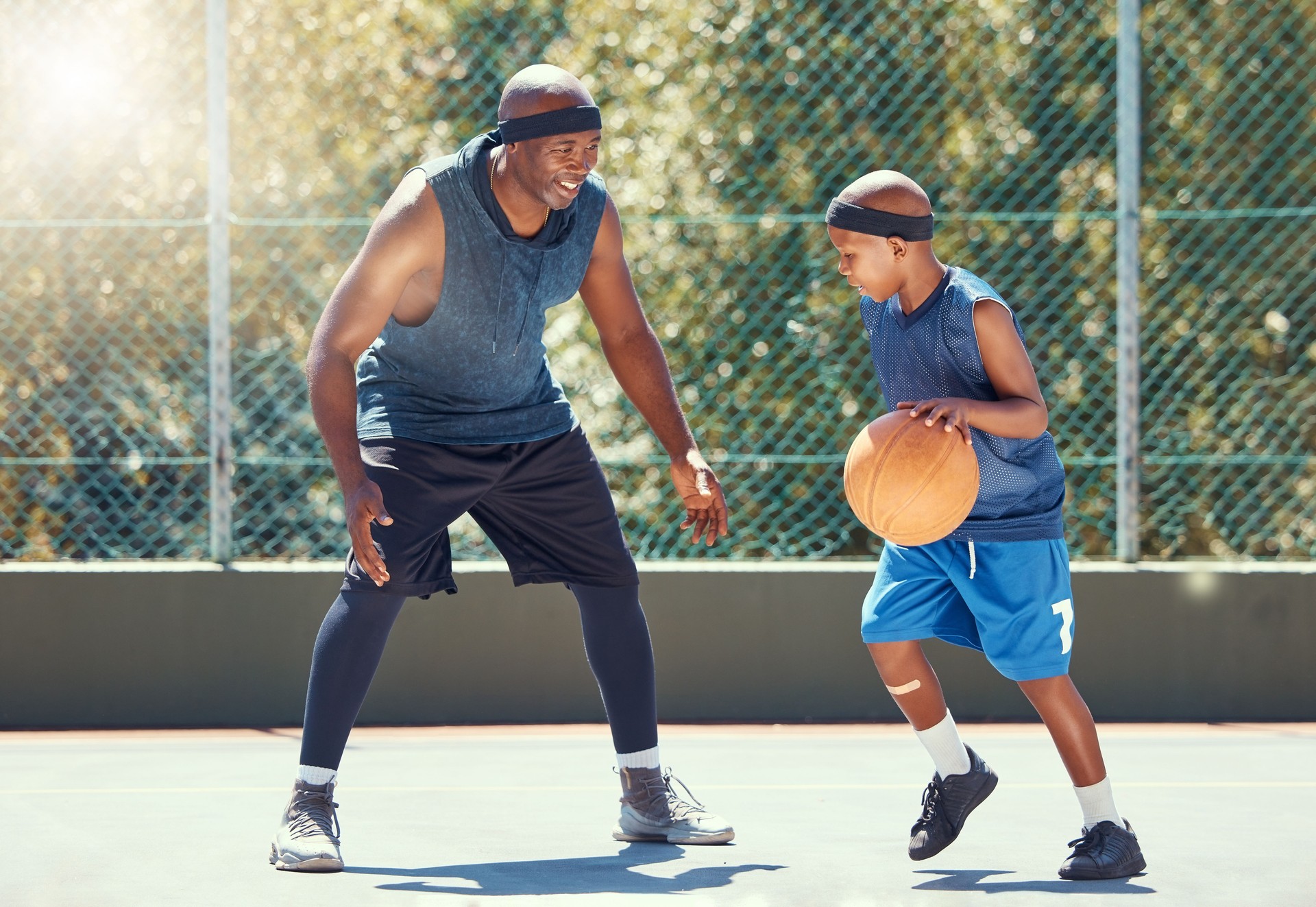 Sport, family and learning basketball with a dad and son training on a court outside for leisure fitness and fun. Black man and kid doing exercise and workout playing a game for health and training