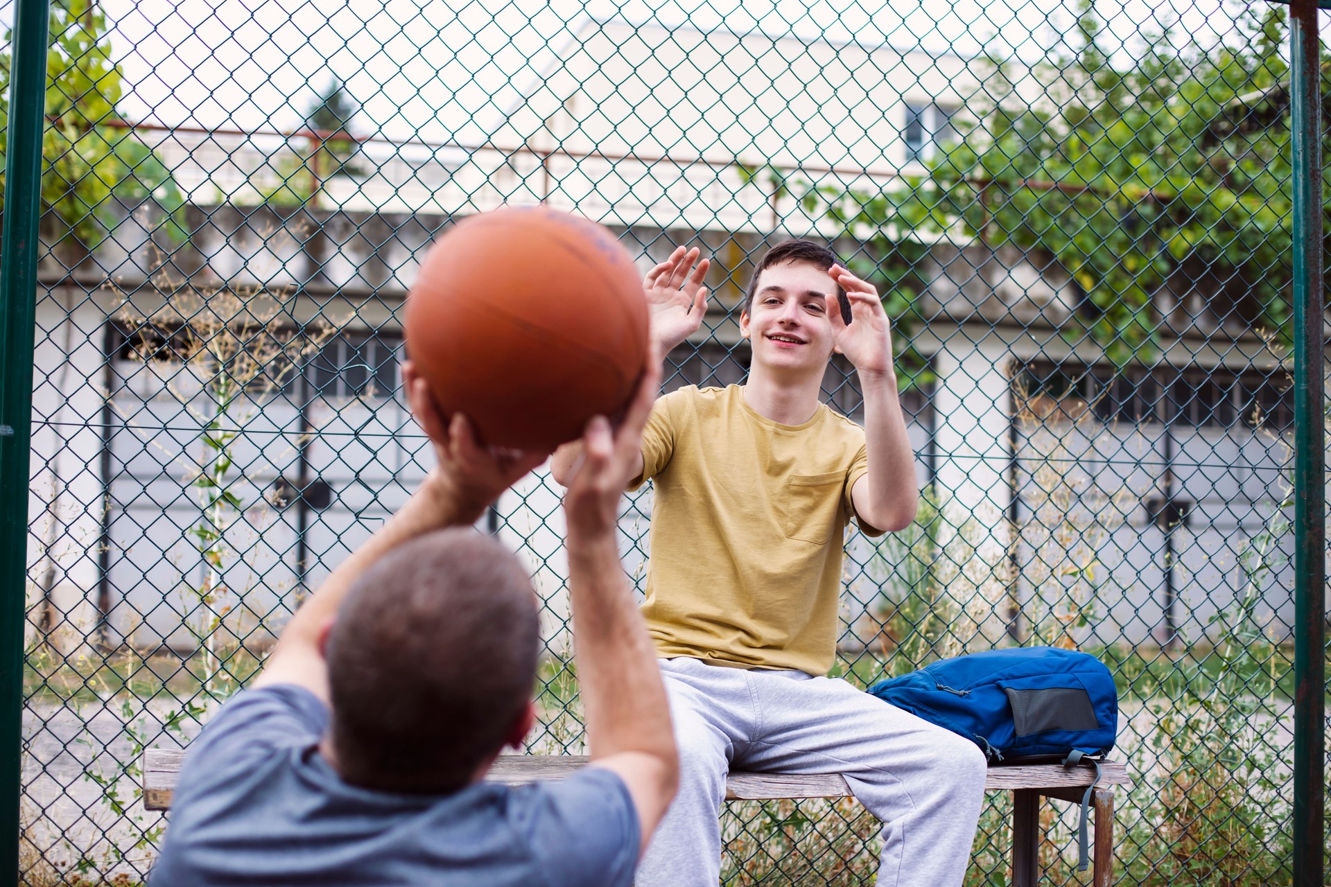 Father teaching and coaching his son how to play basketball on an outdoors basketball court