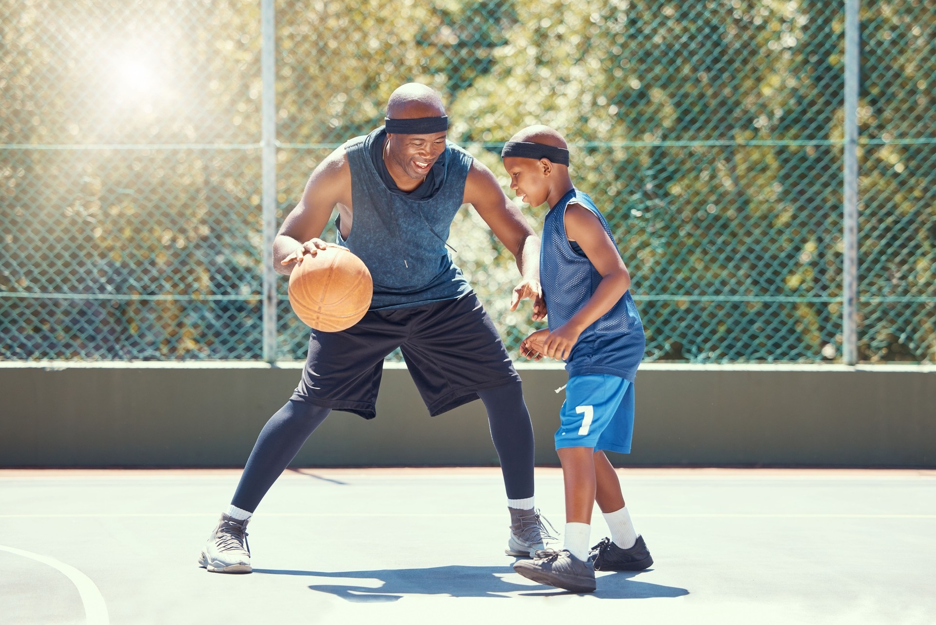Basketball, family and teaching sport with a dad and son training on a court outside for leisure fitness and fun. Black man and kid doing exercise and workout playing a game for health and recreation