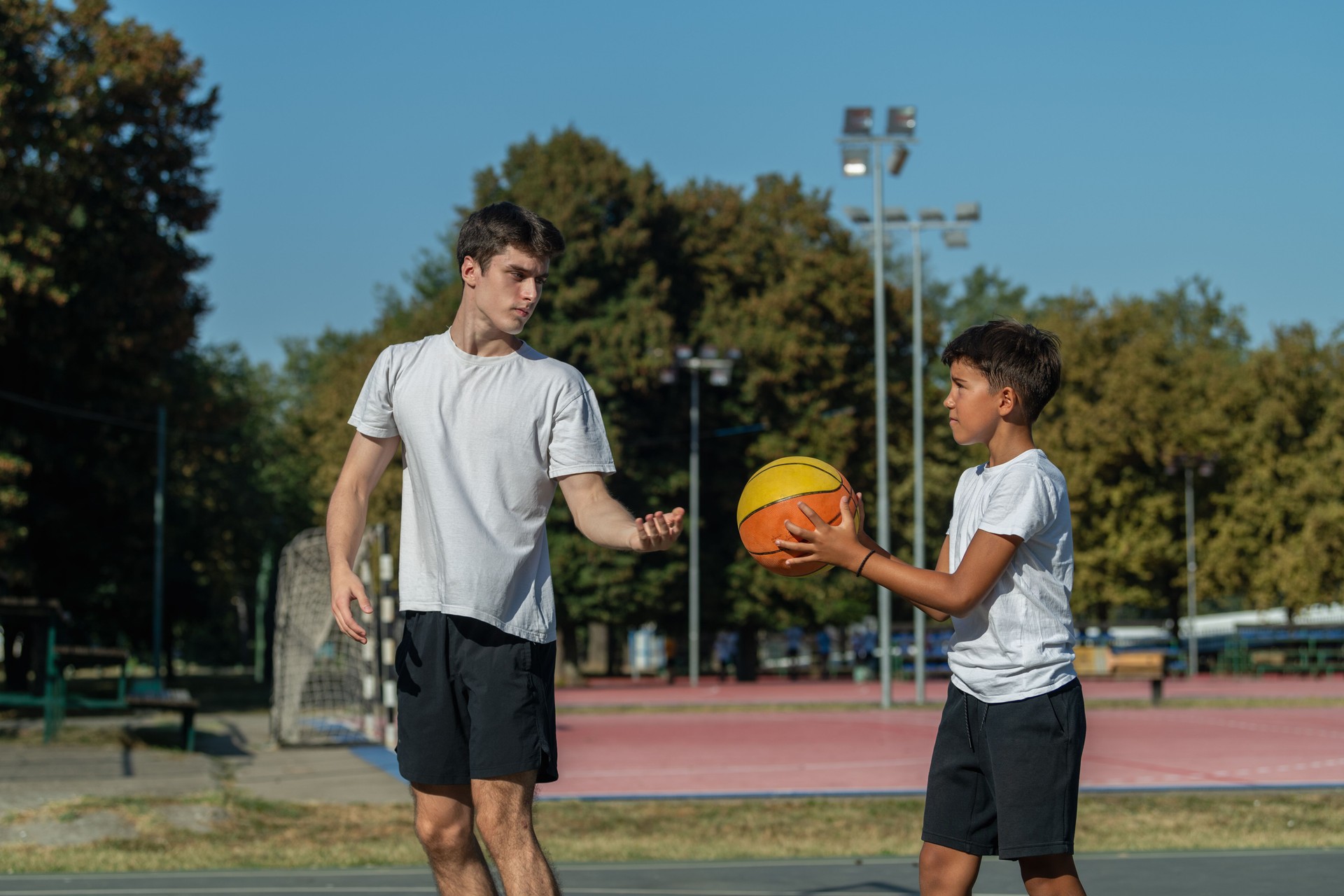 Basketball training session for kids, with a coach teaching technique and skill to a young boy, focusing on sports fundamentals, confidence, and athletic growth
